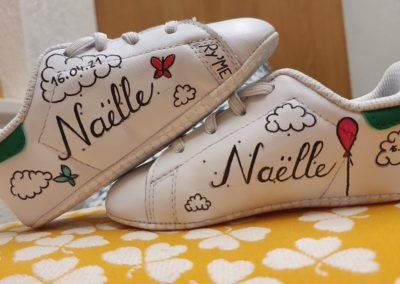 Dessin sur chaussures de bébé pour cadeau de naissance. Petits balons, nuages et papillons. Avec inscriptions Naëlle 16.04.21. création par Lorraine Ryser pour RyLookMe